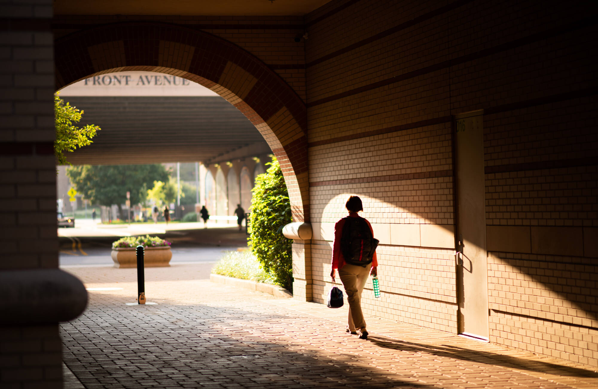 students walking away from camera toward Eberhard Center, crossing underneith campus archway